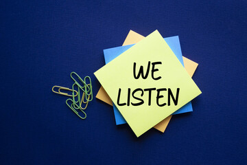 We listen symbol. Yellow sticky note with words We listen. Beautiful deep blue background. Business...