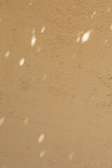 High-resolution image of a beige wall with soft light spots, ideal for backgrounds and textures.