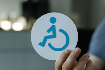 Close-up of a hand holding a paper accessibility symbol.  Perfect for disability awareness...
