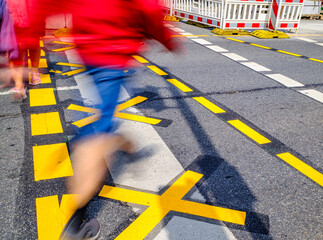 Busy urban street with pedestrians navigating construction zones in bright sunlight during the...