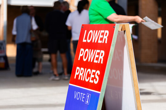 cost of living political sign with out of focus voters waiting to enter polling station