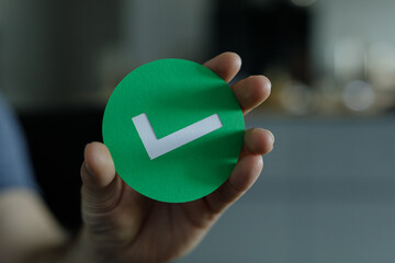 Image of a hand holding a green circle with a white check mark. Perfect for approval, success, or...