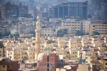 Elegant minaret stands prominently amidst dense cluster of low-rise residential buildings in Cairo,...