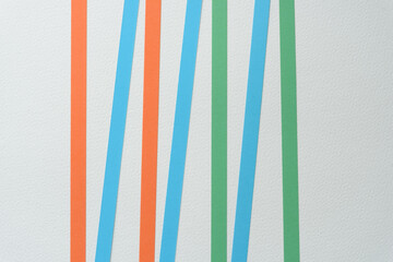 orange and blue and orange paper ribbons arranged with space on blank paper