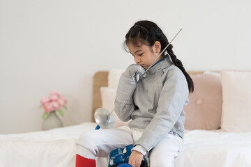 Asian girl in fencing costume and holding sword for practicing and training in gym. Teen girl...