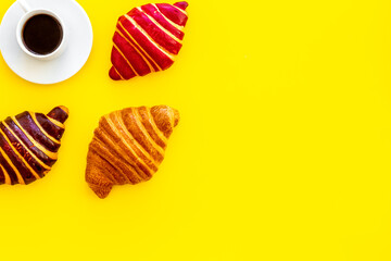 Coffee and croissants on yellow background top view