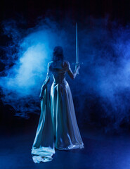 art photo real person fashion model posing, dark silhouette fantasy woman queen holds sword in hands. Black room night blue moon light. Gothic elf girl warrior walking with sharp blade back rear view