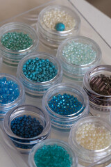 A close-up view of small, colorful seed beads neatly organized in clear plastic containers. Ideal for jewelry making, embroidery, and various DIY craft projects.