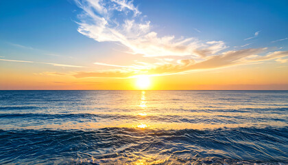 Obraz premium Peaceful golden sunset over ocean with sun on horizon. Calm sea water reflecting beautiful light under blue sky with soft clouds creates serene landscape