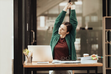 Happy businesswoman warming up body and muscles at workplace, feeling satisfied with work done,...