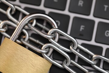 Cyber safety. Metal padlock with chain on laptop, top view