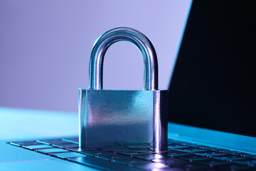 Cyber safety. Metal padlock on laptop in color lights, closeup