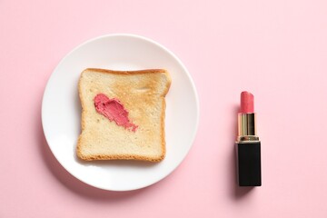 Toast with lipstick on light pink background, flat lay