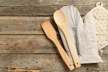 Oven glove and other kitchen utensils on wooden table, flat lay. Space for text