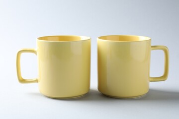 Yellow mugs on light background. Mockup for design