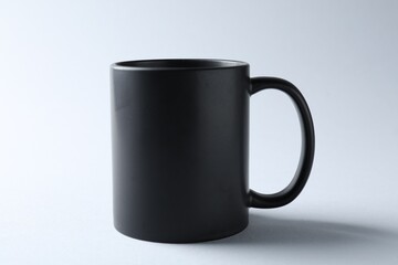 Black mug on light background. Mockup for design