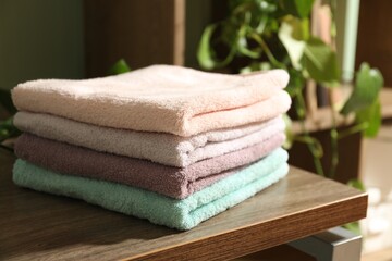 Stack of fresh terry towels on wooden table indoors, closeup