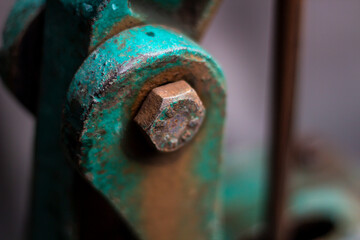 Closeup of a rusty bolt on a weathered teal metal object