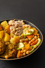 A hearty breakfast features baked sweet potato with carrots and zucchini, chicken breast, lentil cutlets, and kiwi for dessert perfect for a nutritious start