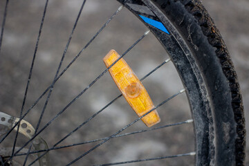 Closeup of a bicycle wheel with a yellow spoke reflector