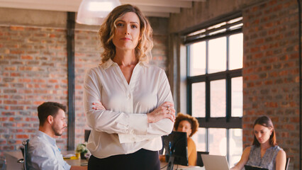 Portrait Of Serious Businesswoman In Office With Colleagues Working In Background