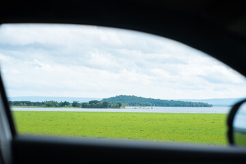 Scenic view of a lush green field by the lake nature photography tranquil environment captured from a car window