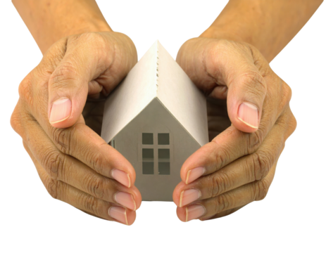 Two hands gently cradling a small white model house with a pitched roof and visible windows.