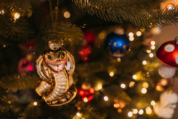 Christmas tree decorated with a golden snake ornament, surrounded by colorful baubles and warm festive lights, creating a unique, lively, and charming holiday atmosphere