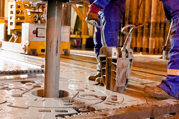 Driller's assistants near the drilling table on oil drilling platform soiled the overalls with...