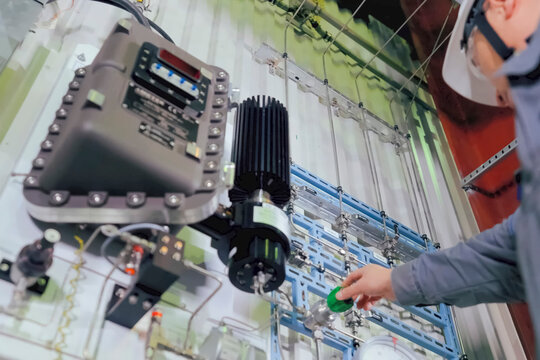 Technicians turning pressure regulator on the monitoring and control panel in the LNG plant