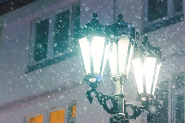 Three lampshades of street lamp against the background of the building in winter it snows.