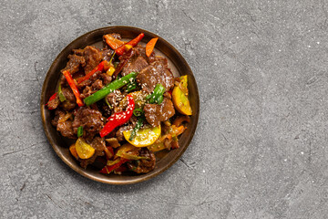 Beef stir fry in a plate top view, Asian meat with vegetables on a grey background
