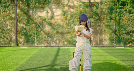 Indian gen z athlete sports woman lady standing outdoor wear white uniform look camera Asian young, adult cricket player female girl hold bat staring cam day time at match play ground 
