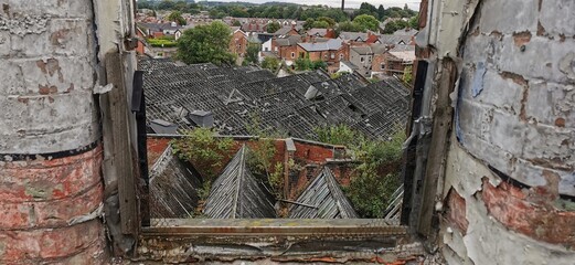 Urban view from broken window overlooking village. Rotting brickwork framing town mill ruins below....