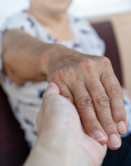 Elderly female hand holding hand of young caregiver at nursing home.Geriatric doctor or geriatrician concept. Doctor physician hand on happy elderly senior patient to comfort in hospital examination