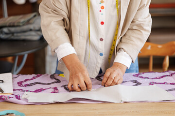 woman folding fabric, preparing it for the next step in the sewing process on the table.