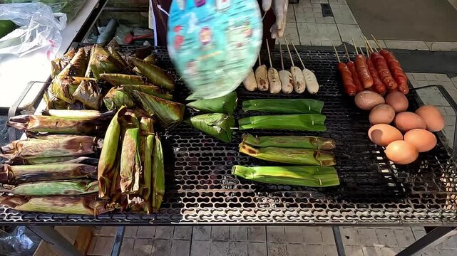 Street food vendor selling grilled egg or kai ping, aeb or fish wrapped banana leaves, skewers and sausages that shows the authentic local thai food. Chiang mai, Thailand