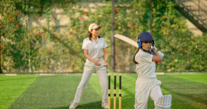 Indian gen z young adult sports woman girl standing at outdoor match play ground wear gloves white uniform and protective helmet Asian athlete cricket player female lady hold bat do practice day time