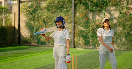 Indian gen z young adult woman lady wear hand gloves white dress leg guard helmet day time cricket happy player sports teen female girl hold bat play casual match game do batting at ground place