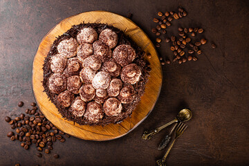 Whole tiramisu cake with chocolate and whipped cream on dark background top view