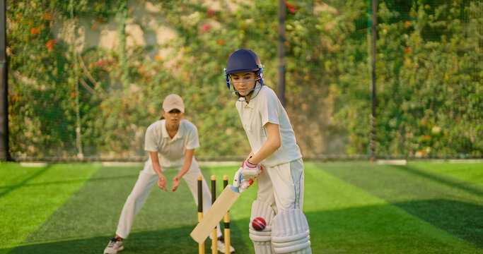 Indian gen z young adult athlete sports woman girl standing at outdoor match play ground wear gloves white uniform protective helmet Asian cricket player female lady hold bat hitting ball do practice