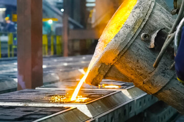 Pouring molten metal into mold from a special container. Factory