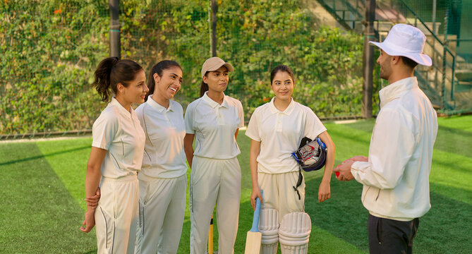 Indian asian young adult gen z woman lady group team standing coach man do sports discussion at match male guy trainer explain game strategy girls female player wear white uniform outdoor play ground