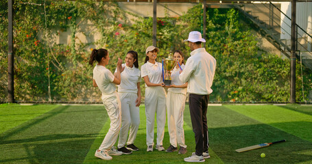 Indian asian young adult gen z sports woman lady group team with coach man win cricket match hold trophy do celebrate male trainer female player give high five cheering have fun joy play ground