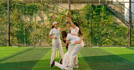 Indian young adult gen z sports woman lady group win match held award in hand raise up enjoy day time happy female team cheering have fun joy do hug shout loud scream yes at play ground place