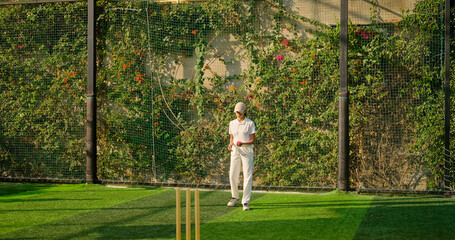 Indian young adult gen z bowler woman lady standing at match ground wear white uniform with cap. Asian teen age female girl running play cricket learn game do practice to hit wicket throw ball place