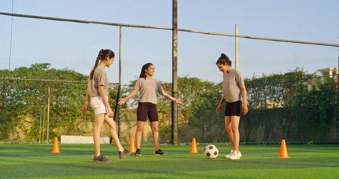 Indian happy young adult gen z group sports woman lady play football learn at outdoor yard female girl players practice game kicking soccer ball enjoy team outside ground place day time