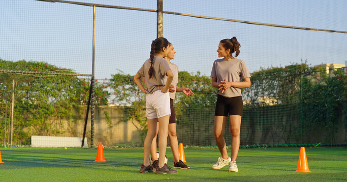 Indian happy young adult gen z group sports woman lady play football learn at outdoor yard female girl players practice game kicking soccer ball enjoy team break time after match outside ground place