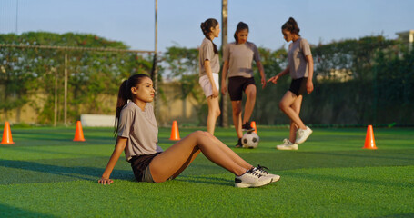 Indian young adult woman lady group team play football enjoy day have fun joy outdoor place tired upset sad gen z female girl player sitting on ground take rest time relax break after sport game