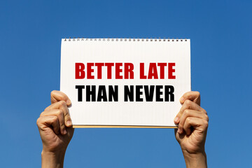 Better late than never text on paper holding by a woman's hand with blue sky background